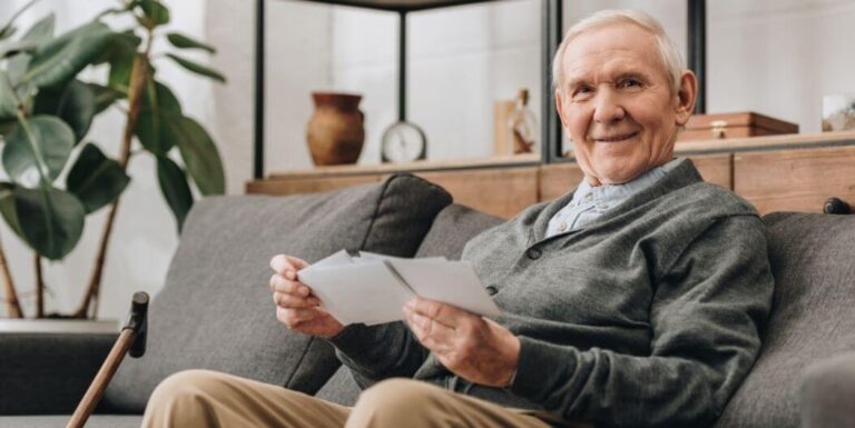Elderly Man Smiling While Reading Letters in Memory Care Facility